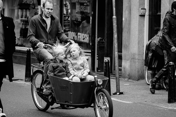 Amsterdam, Nederländerna - 9 maj: Pappa med två barn ridning cyklar i historiska delen i Amsterdam, Nederländerna den 9 maj 2015 — Stockfoto