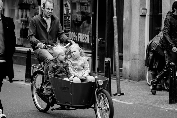 AMSTERDAM, PAÍSES BAJOS - 9 DE MAYO: Padre con dos hijos montando bicicletas en parte histórica en Amsterdam, Holanda el 9 de mayo de 2015 —  Fotos de Stock