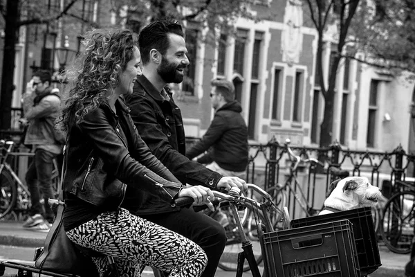 Amsterdam, Holandia - 9 maja: Mężczyzna i kobieta z psem jazdy rowerami w zabytkowej części w Amsterdam, Holandia na 9 maja 2015 — Zdjęcie stockowe