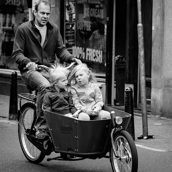 Amsterdam, Nederländerna - 9 maj: Pappa med två barn ridning cyklar i historiska delen i Amsterdam, Nederländerna den 9 maj 2015 — Stockfoto