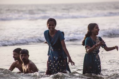 VARKALA, KERALA, INDIA - DECEMBER 15 , 2012: Unidentified Hindu family do holy bathe at the sacred confluence on  Papanasam beach clipart