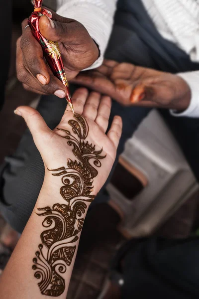 VARANASI , INDIA-  NOVEMBER 13, 2012: indian street  master uses  henna paste or mehndi application on white  tourist woman hand. Traditional Indian natural skin decoration, bio-tattoo — Stock Photo, Image