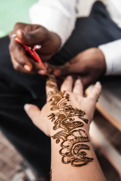 VARANASI , INDIA-  NOVEMBER 13, 2012: indian street  master uses  henna paste or mehndi application on white  tourist woman hand. Traditional Indian natural skin decoration, bio-tattoo — Stock Photo, Image