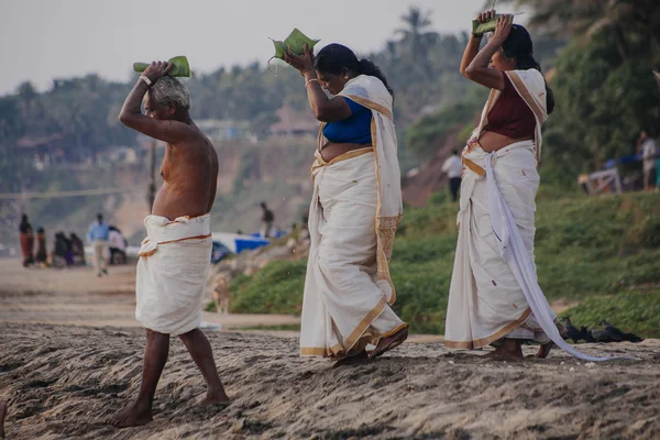 VARKALA, INDIA - DEC 15, 2012: I pellegrini scendono al mare per celebrare il puja. Questo e 'un luogo sacro. I pellegrini vengono qui per fare un tuffo nelle acque sante della spiaggia . — Foto Stock