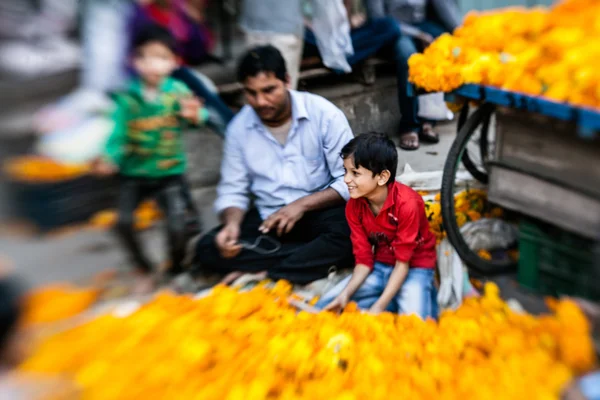 Man threading colourful flower garlands — Stock Photo, Image