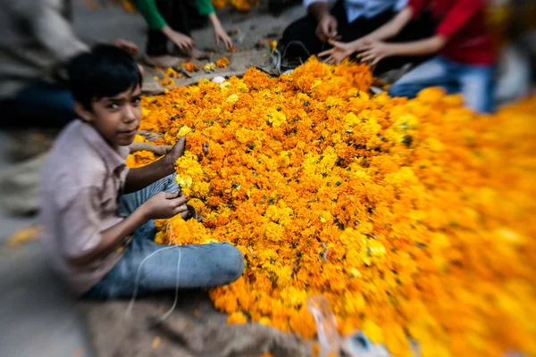 Mann fädelt bunte Blumengirlanden ein — Stockfoto
