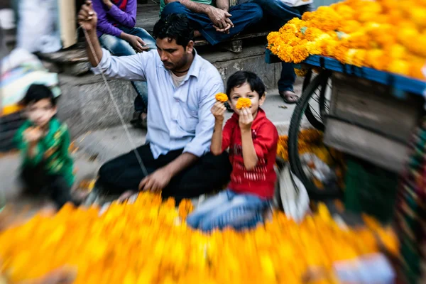 Mann fädelt bunte Blumengirlanden ein — Stockfoto