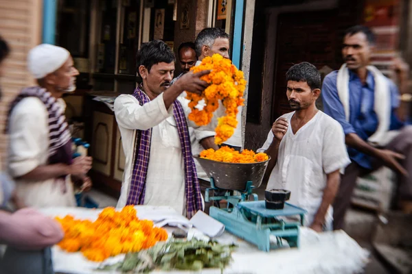 Homem enfiando guirlandas de flores coloridas — Fotografia de Stock