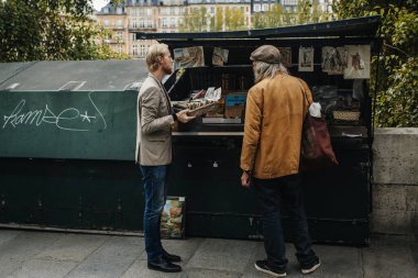 PARIS, FRANCE - 7 Ekim 2016: Notre-Dame katedralinin önündeki Seine nehrinin kenarındaki geleneksel Bouquiniste standı. Buketler kullanılmış ve antika kitapların yanı sıra hediyelik eşya da satıyorlar..