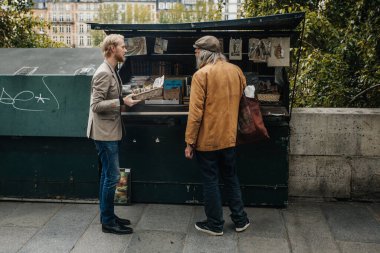 PARIS, FRANCE - 7 Ekim 2016: Notre-Dame katedralinin önündeki Seine nehrinin kenarındaki geleneksel Bouquiniste standı. Buketler kullanılmış ve antika kitapların yanı sıra hediyelik eşya da satıyorlar..