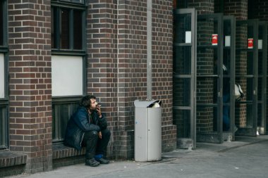 BERLİN, Almanya - 3 HAZİRAN 2015: Berlin, Almanya 'da tren istasyonu yakınlarındaki bir yolun kenarında mola veren evsiz adam.