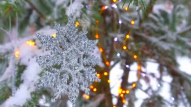 Kışın karlı ormandaki köknar ağacında Noel için kar taneleri ve ışıklar.