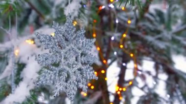 Kışın karlı ormandaki köknar ağacında Noel için kar taneleri ve ışıklar.