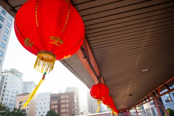 Overhead pedestrian walking bridge with traditional chinese red lamps leads to nearby facilities.