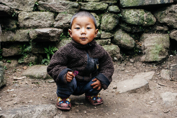 HIMALAYAS, EVEREST REGION, NEPAL - OCTOBER 20, 2018 : Portrait nepalese  small boy  near their house, on the street in Himalayan village, Nepal