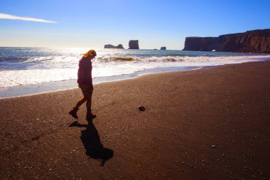 Gün batımında İzlanda sahilinde bir kadın.