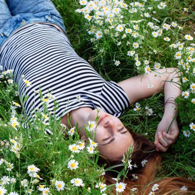 Kahverengi saçlı güzel bir kadın, gülümsüyor, papatya tarlasında.