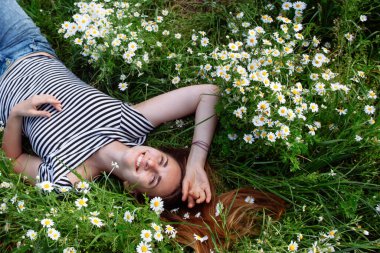 Kahverengi saçlı güzel bir kadın, gülümsüyor, papatya tarlasında.