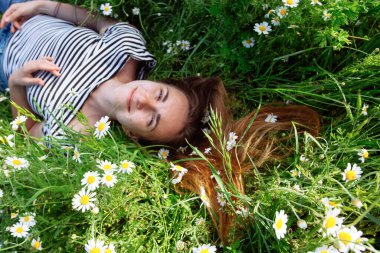 Kahverengi saçlı güzel bir kadın, gülümsüyor, papatya tarlasında.
