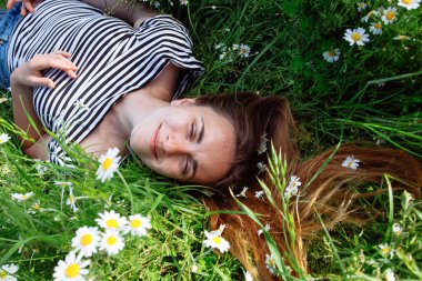 Kahverengi saçlı güzel bir kadın, gülümsüyor, papatya tarlasında.