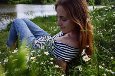 Kahverengi saçlı güzel bir kadın, gülümsüyor, papatya tarlasında.