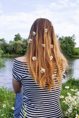 Kahverengi saçlı güzel bir kadın, gülümsüyor, papatya tarlasında.