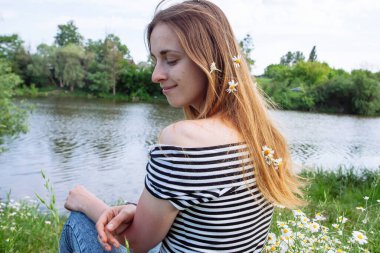 Kahverengi saçlı güzel bir kadın, gülümsüyor, papatya tarlasında.