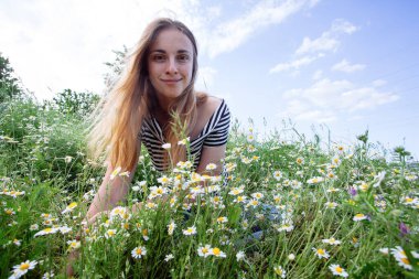 Kahverengi saçlı güzel bir kadın, gülümsüyor, papatya tarlasında.
