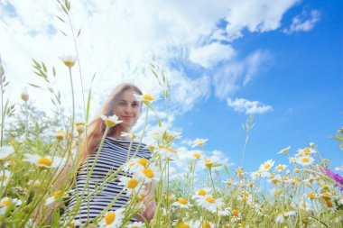 Kahverengi saçlı güzel bir kadın, gülümsüyor, papatya tarlasında.