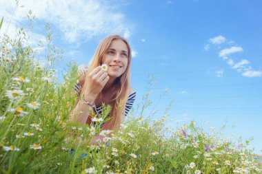Kahverengi saçlı güzel bir kadın, gülümsüyor, papatya tarlasında.