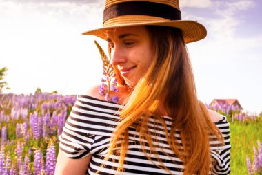 Lupin tarlasında şapkalı güzel bir kadın.