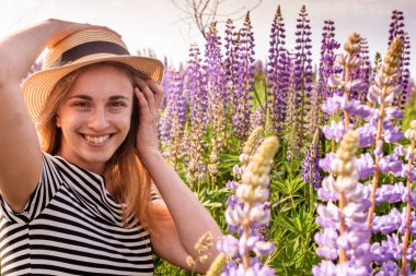 Lupin tarlasında şapkalı güzel bir kadın.