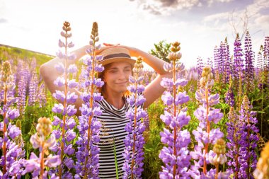 Lupin tarlasında şapkalı güzel bir kadın.