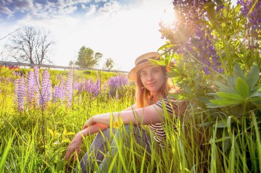 Lupin tarlasında şapkalı güzel bir kadın.