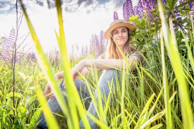 Lupin tarlasında şapkalı güzel bir kadın.