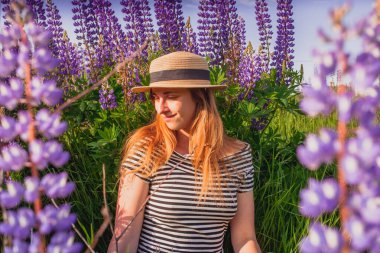 Lupin tarlasında şapkalı güzel bir kadın.