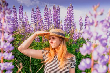 Lupin tarlasında şapkalı güzel bir kadın.
