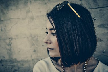 Şehir ortamında beton duvara yaslanan yalnız bir kadın..