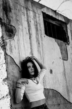 Şehir ortamında beton duvara yaslanan yalnız bir kadın..