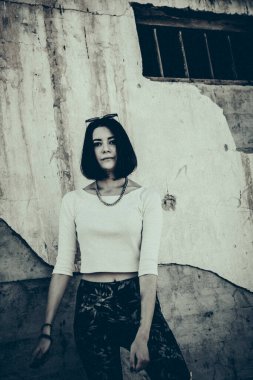 Şehir ortamında beton duvara yaslanan yalnız bir kadın..