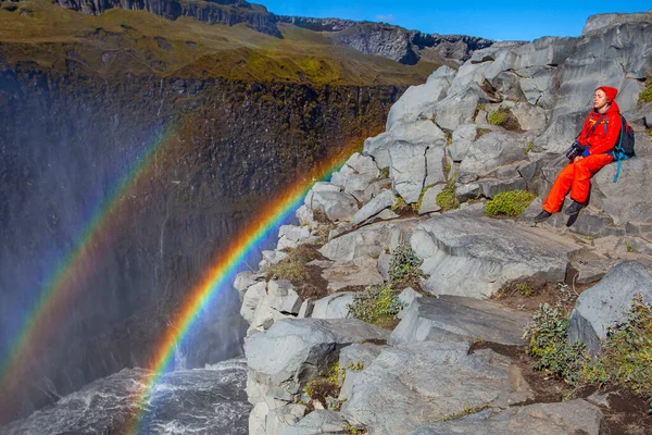 Detifoss şelalesinin yanındaki kırmızı elbiseli kadın çift gökkuşağı, İzlanda
