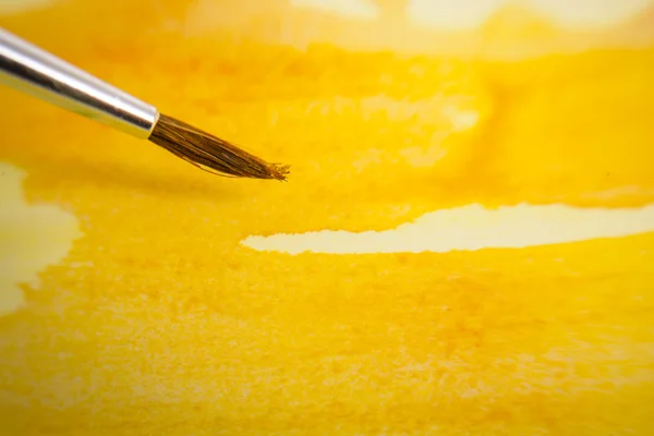 Yellow painted background and brush — Stock Photo, Image