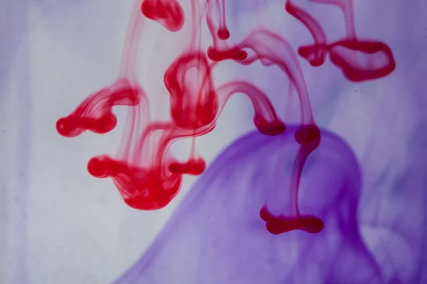 Röda och violetta vätska i vatten — Stockfoto