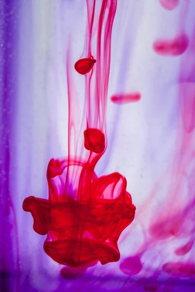 Rood en violet vloeistof in water — Stockfoto