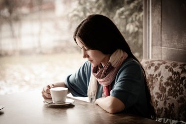 Beautiful young woman with a cup of tea at a cafe clipart
