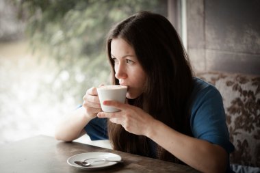 Kafede bir fincan çay içen güzel genç bir kadın.
