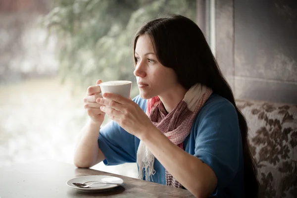 Beautiful young woman with a cup of tea at a cafe — Stock Photo, Image