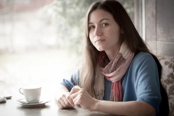 Schöne junge Frau mit einer Tasse Tee in einem Café — Stockfoto