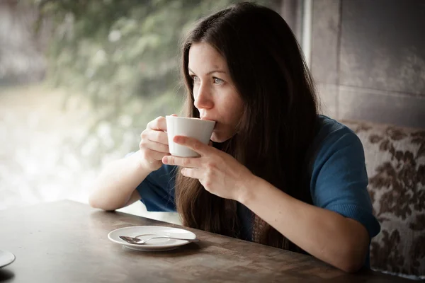 Beautiful young woman with a cup of tea at a cafe — Stock Photo, Image
