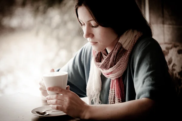 Beautiful young woman with a cup of tea at a cafe — Stock Photo, Image